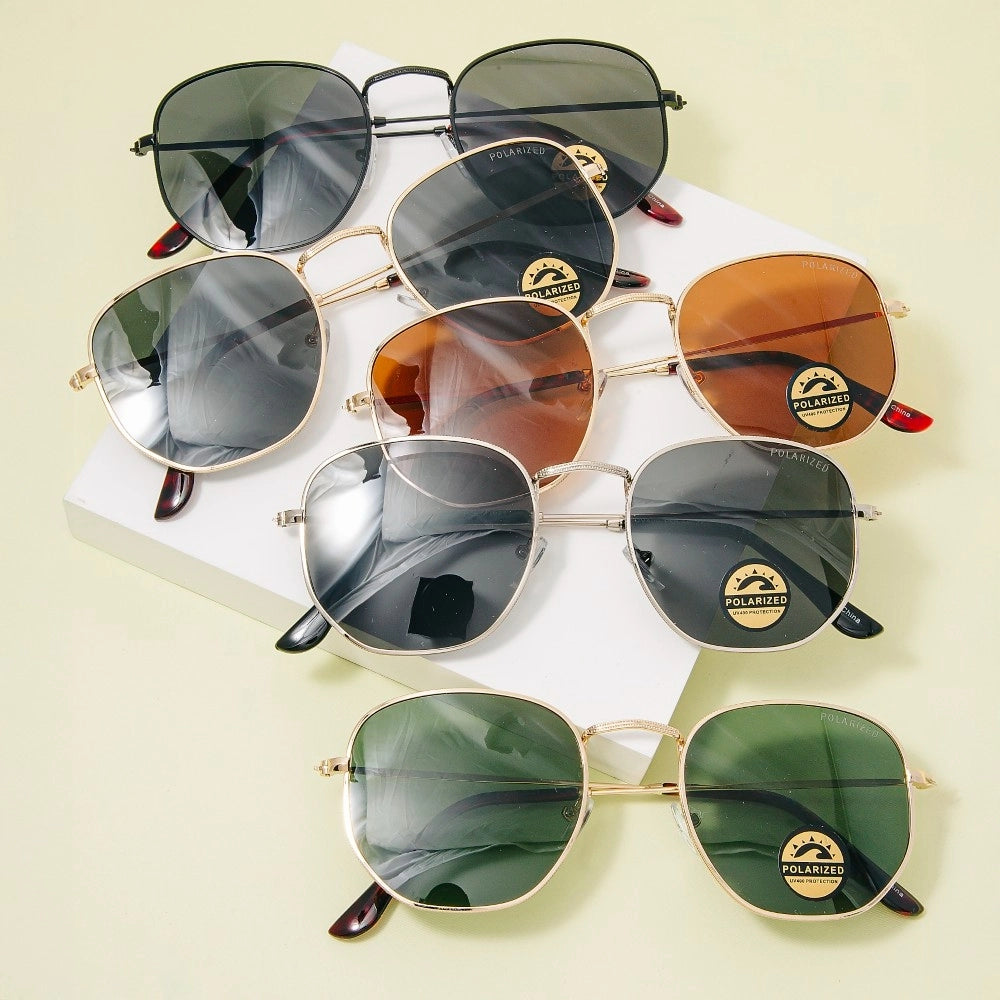 Collection of sunglasses with different lens colors and gold frames on a light background