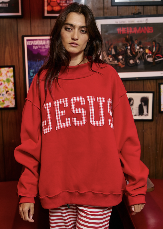 A woman wearing a red oversized sweatshirt with &