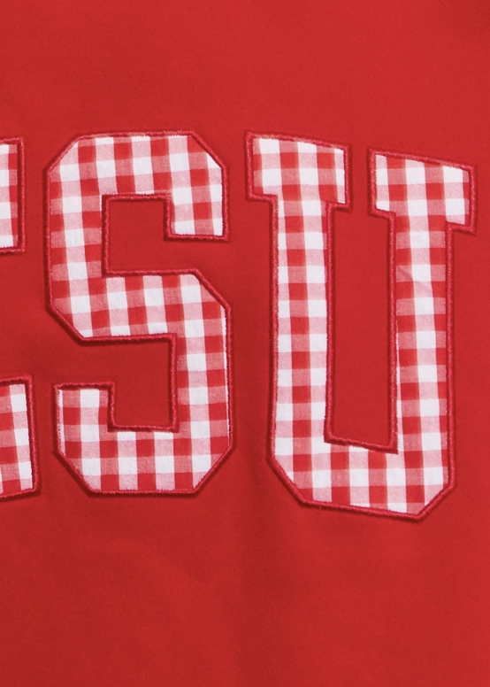 Close-up of a red garment featuring large collegiate-style letters outlined in red, filled with a red-and-white gingham check pattern.