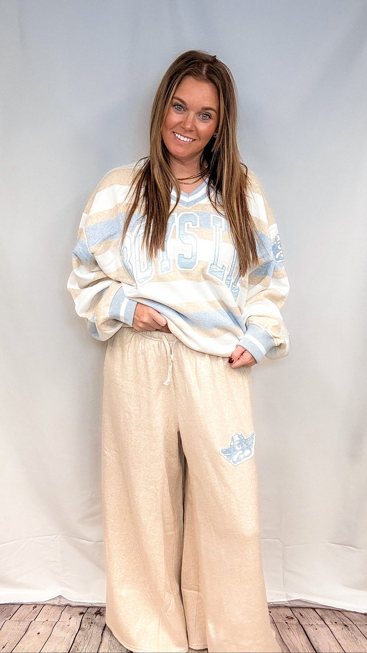 Woman wearing blue, beige and white stripe top with &