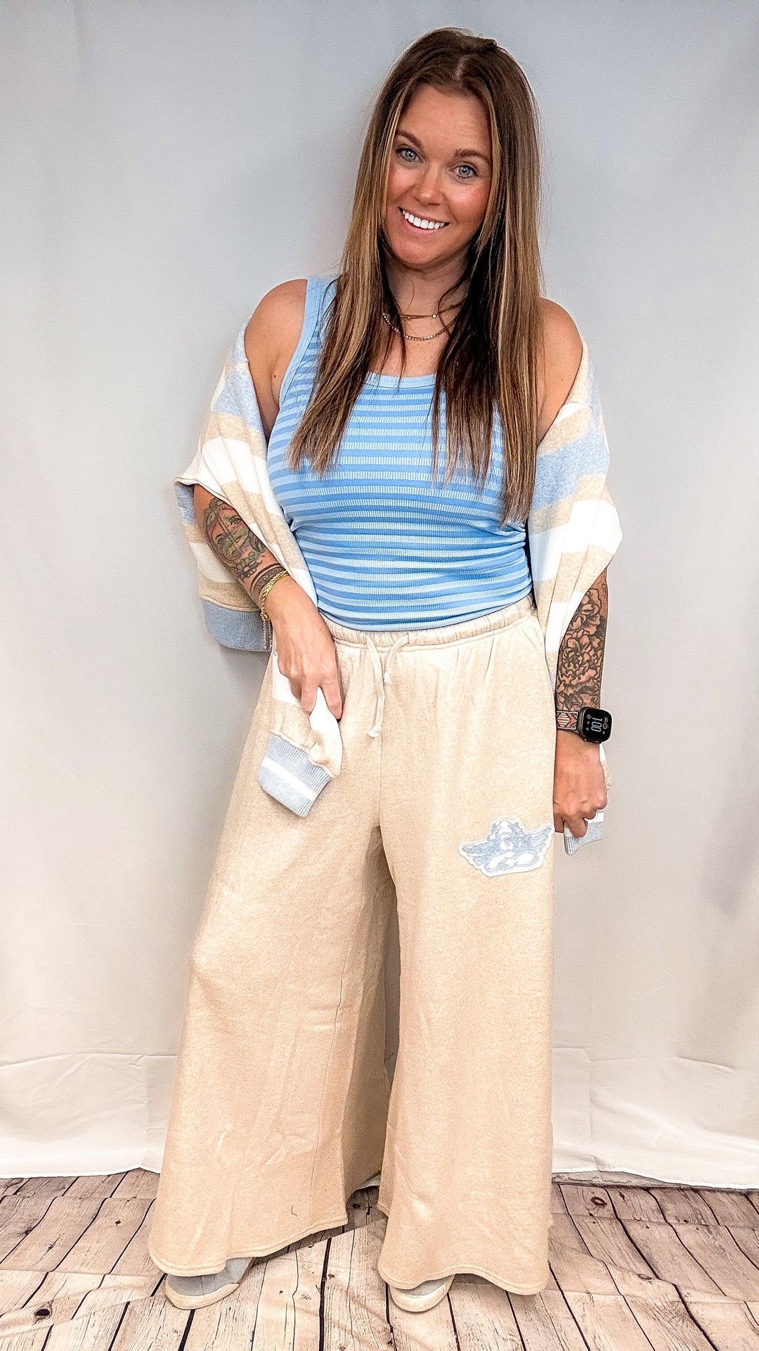 Woman wearing blue stripe tank top with beige pants on white background
