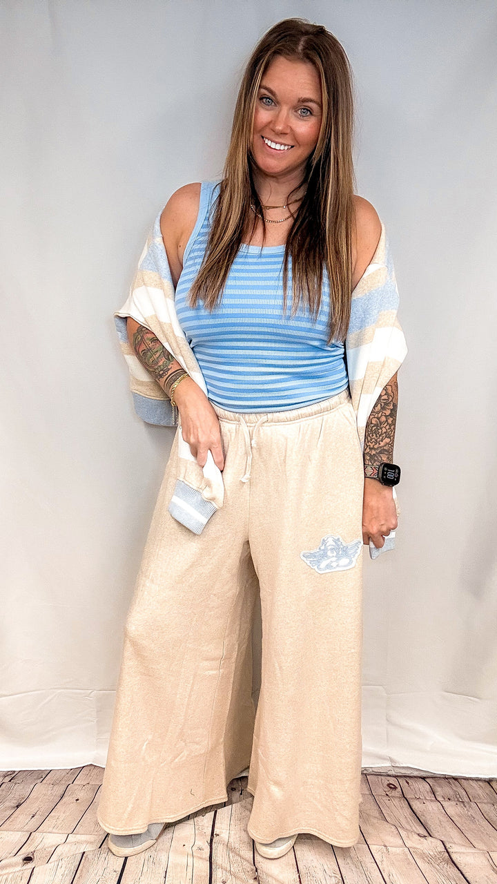 Woman wearing blue stripe tank top with beige pants on white background