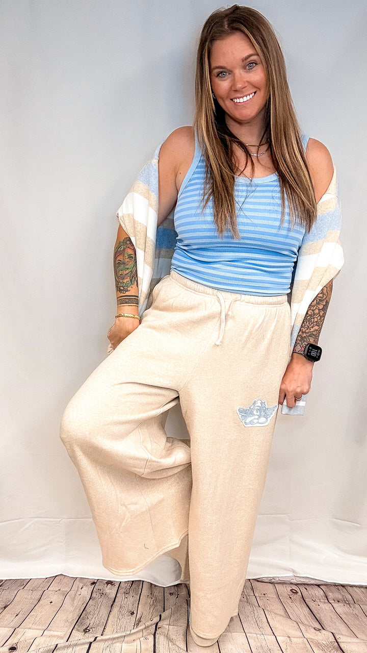 Woman wearing blue stripe tank top with beige pants on white background