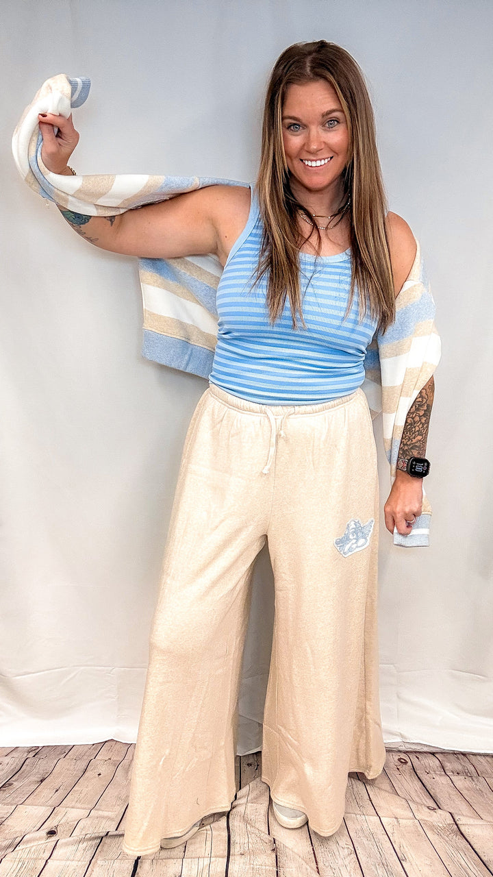 Woman wearing blue stripe tank top with beige pants on white background