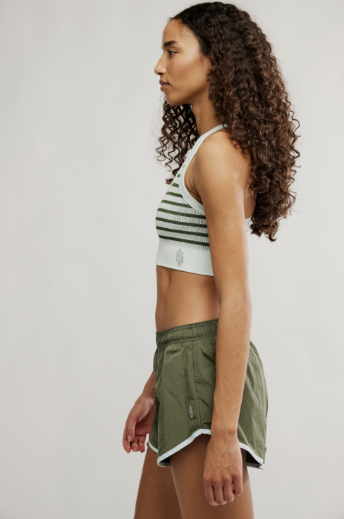 Woman wearing a striped sports bra and green shorts on a white background