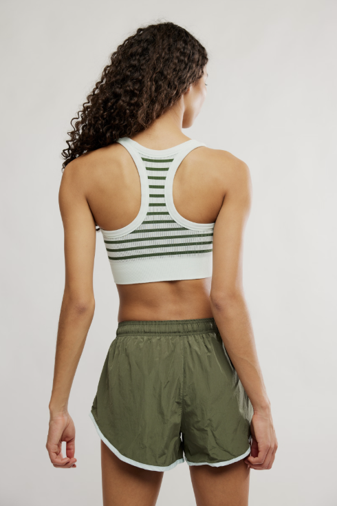Person wearing a sports bra and shorts on a plain background