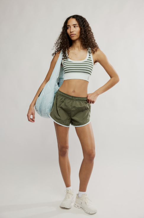 Woman wearing a striped tank top and green shorts on a plain background