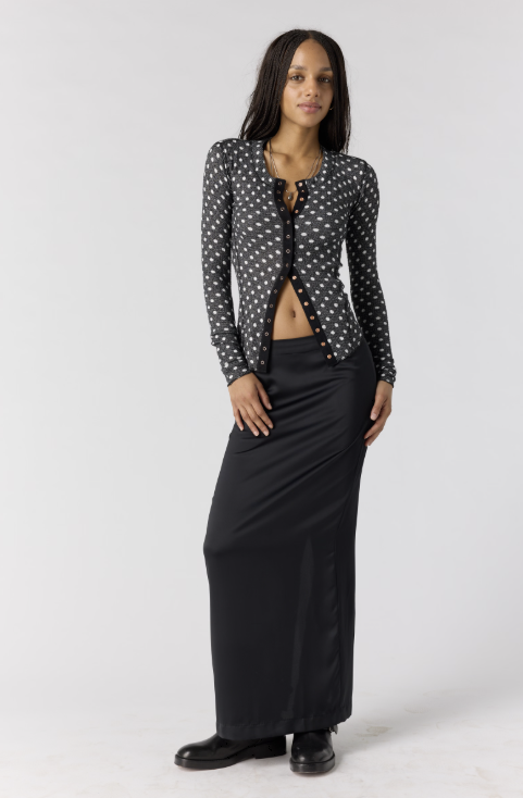 Woman wearing black cardigan with white polka dots with black skirt on white background