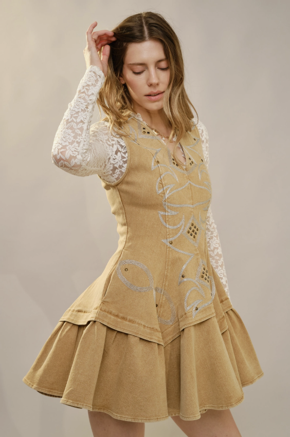 Woman wearing a beige dress with white lace sleeves against a neutral background
