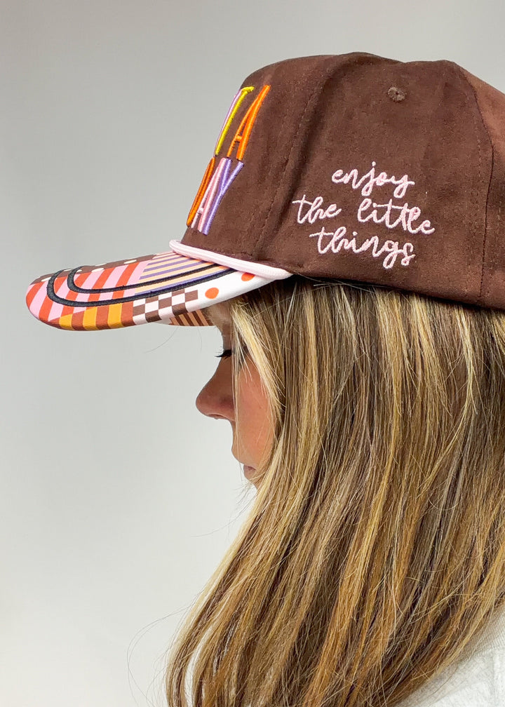 Woman shown from side view wearing brown faux suede hat with &