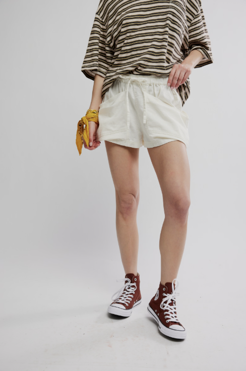 Person wearing a striped shirt, white shorts, and high-top sneakers on a plain background