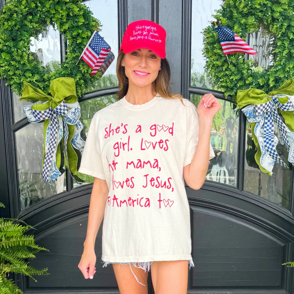 Woman wearing graphic tee and red hat standing outdoors