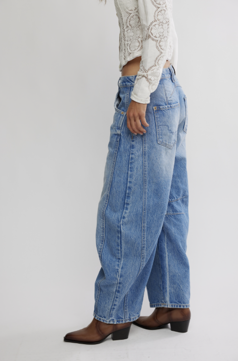 Person wearing blue jeans and brown boots on a white background