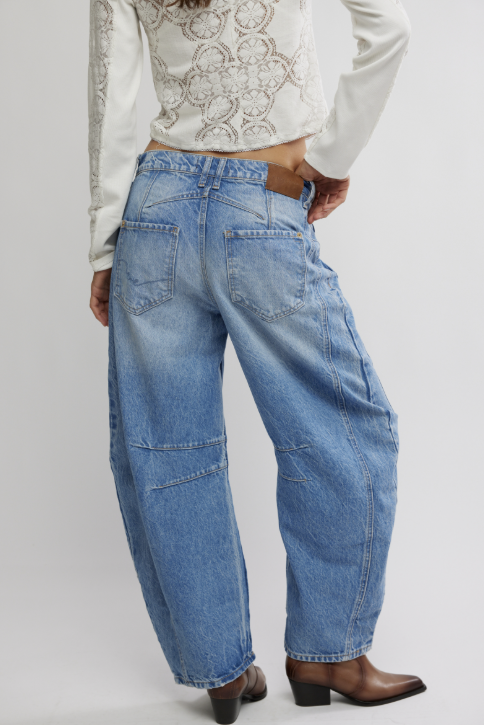 Person wearing blue jeans and a white cropped top on a plain background