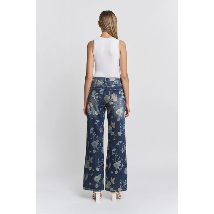 Woman wearing a white sleeveless top and blue floral pants on a white background