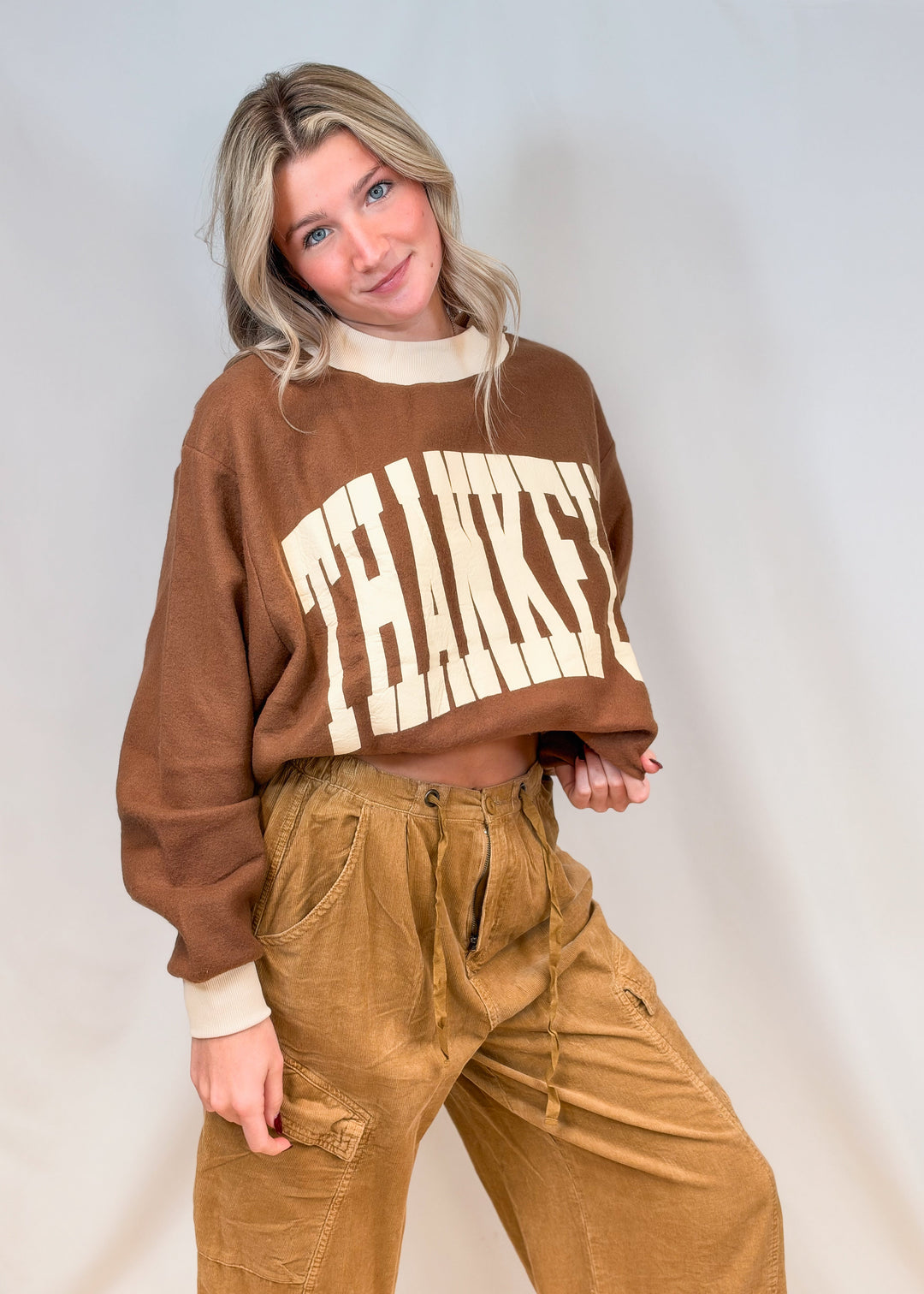 Woman wearing brown mock neck sweatshirt with beige &