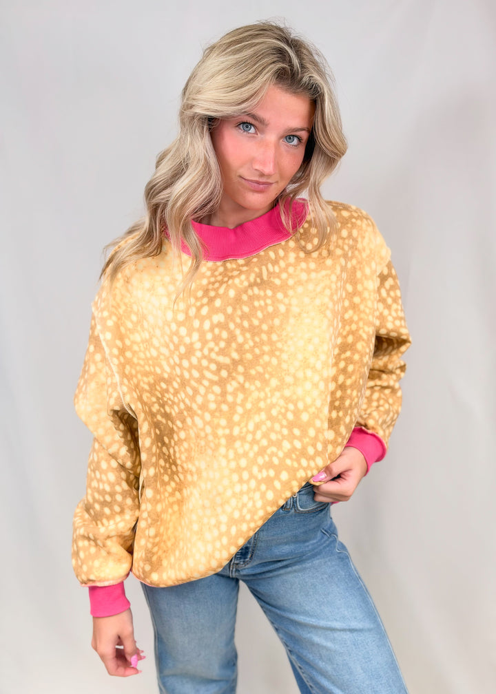 Woman wearing fawn printed mock neck sweatshirt with pink ribbed detail on neck and cuffs on plain background