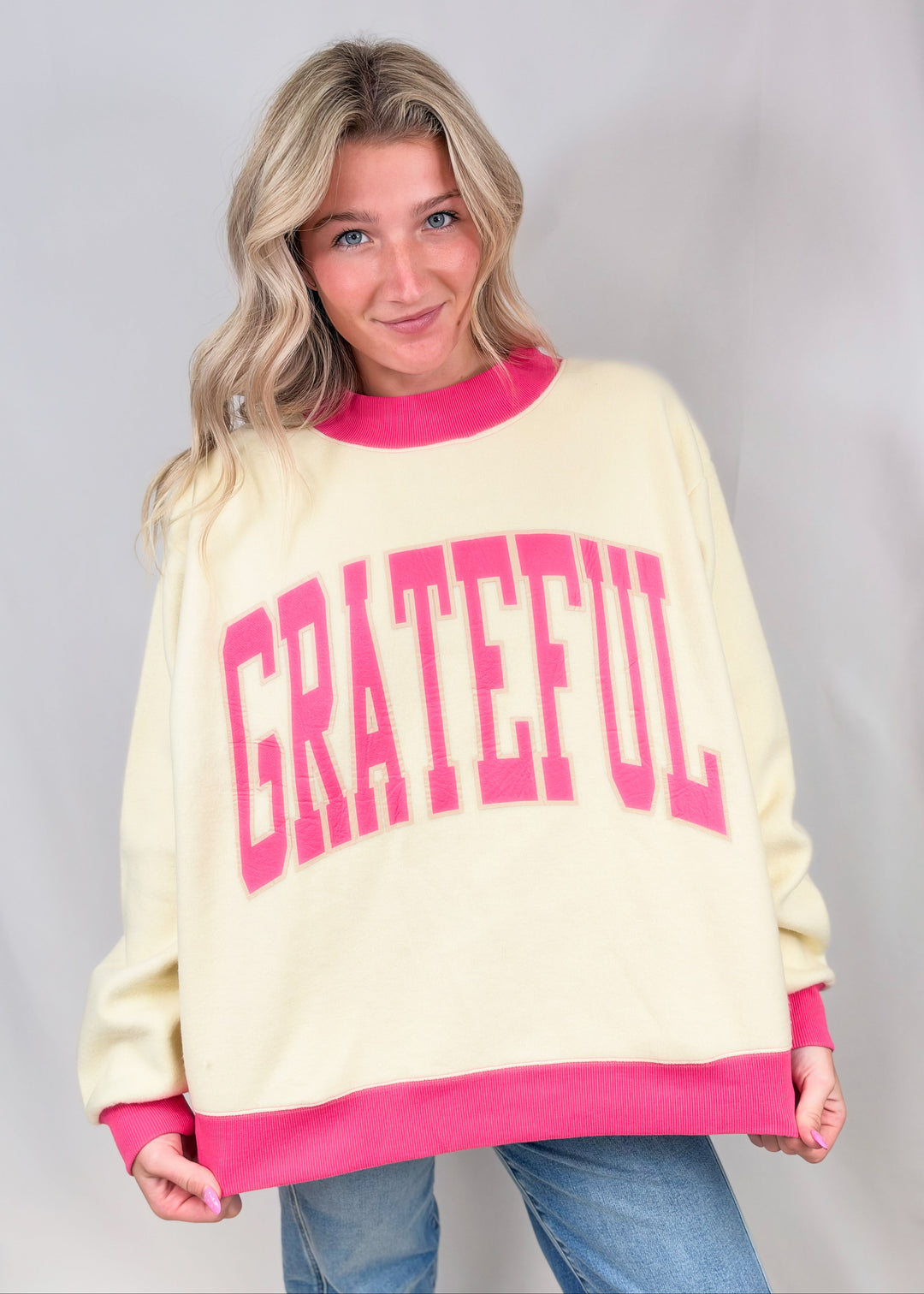Woman wearing beige mock neck sweatshirt with &