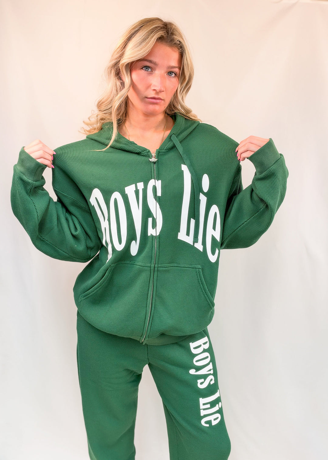 Woman wearing green zip up sweatshirt with &
