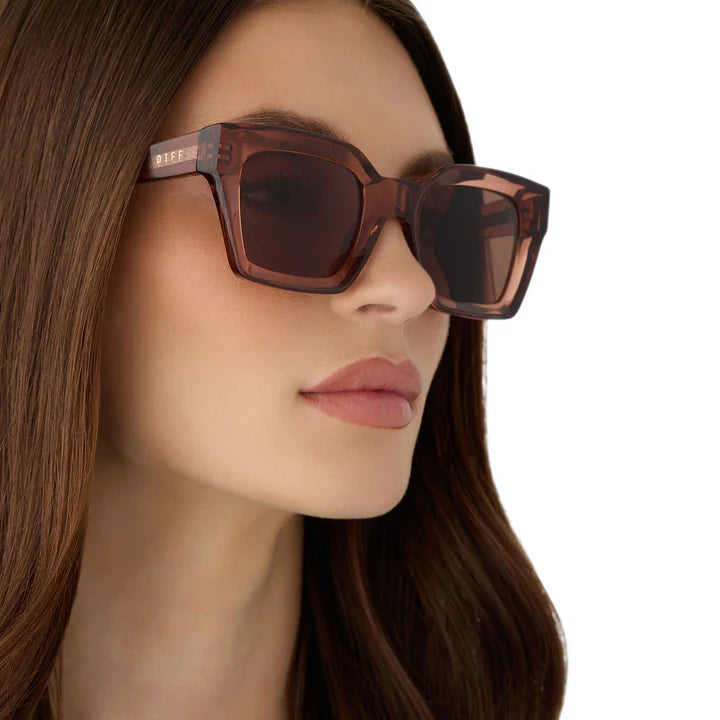 Close-up of a woman wearing brown sunglasses with a blurred background