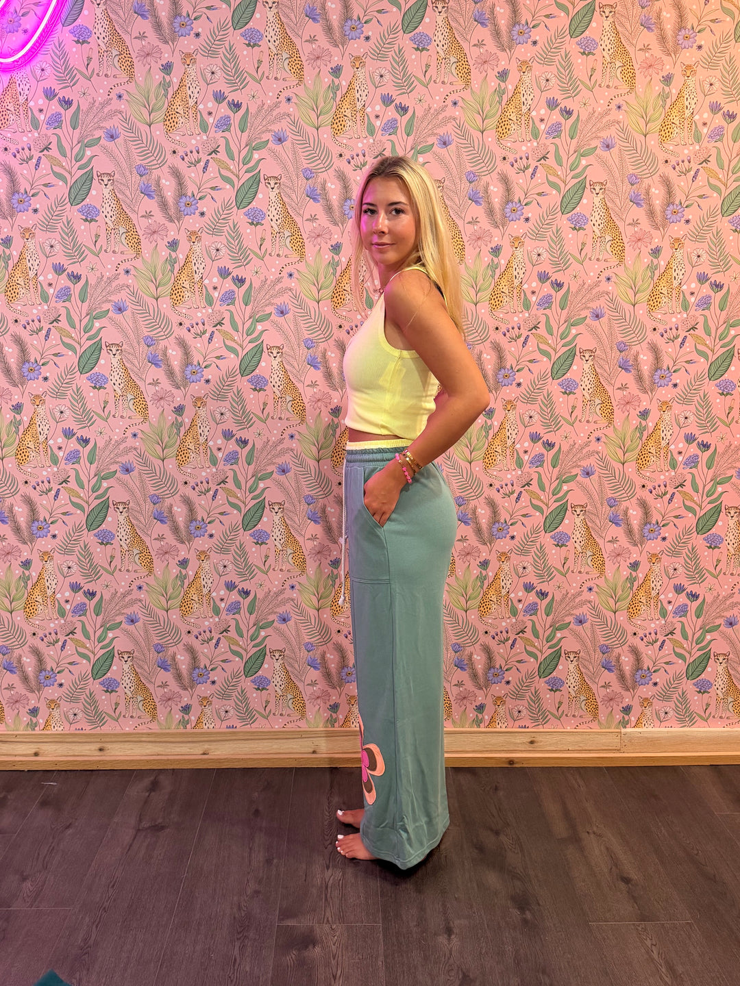 Woman posing in front of a pink floral wallpapered wall