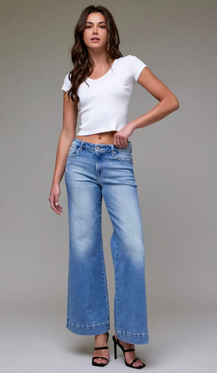 Woman wearing a white top and blue jeans on a plain background