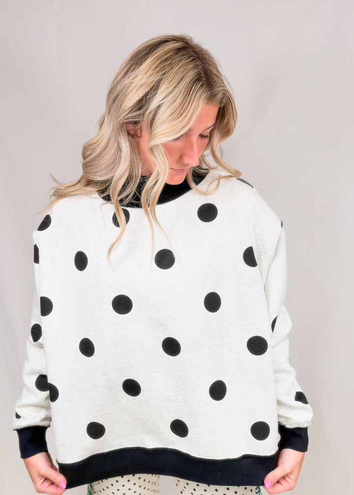 Woman wearing black and white polka dot mock neck on plain background