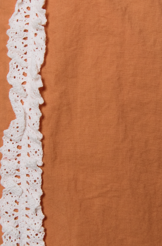 Brown fabric with white lace trim on a brown background