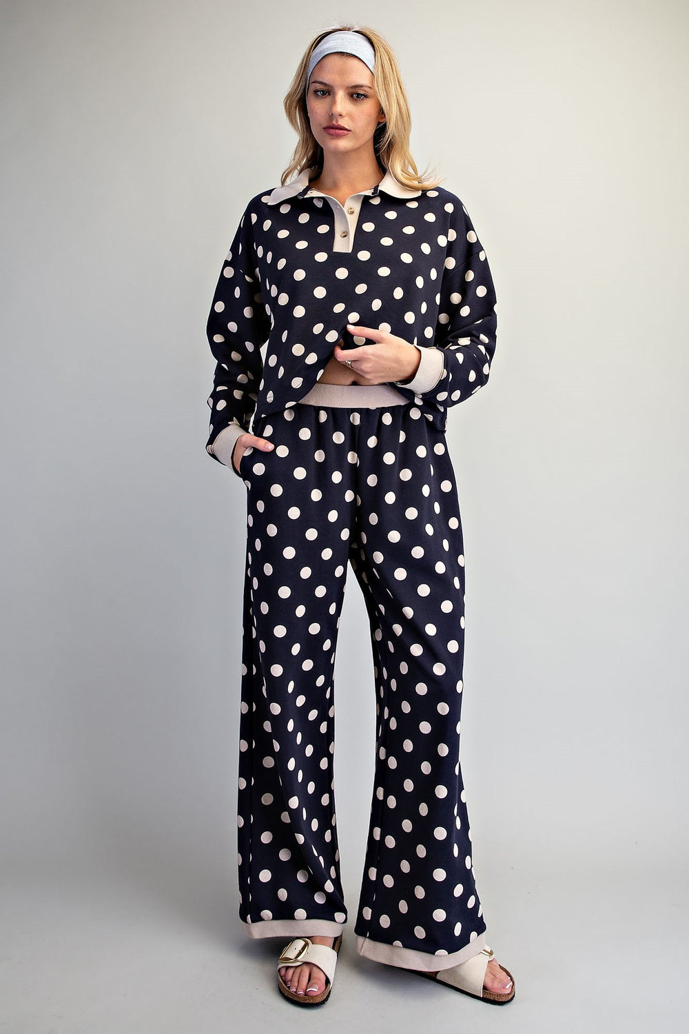 Woman wearing matching navy and beige polka dot set on plain background