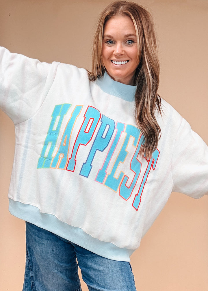 A woman wearing a white mock-neck sweatshirt with &