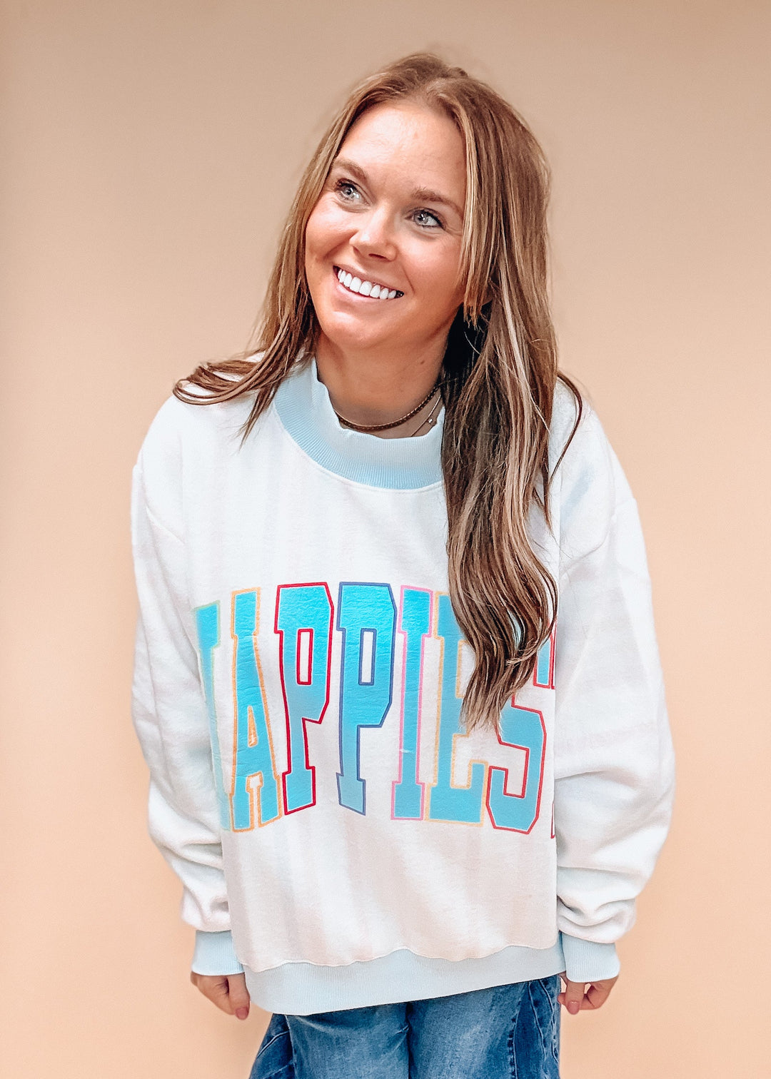 A woman wearing a white crewneck sweatshirt with &