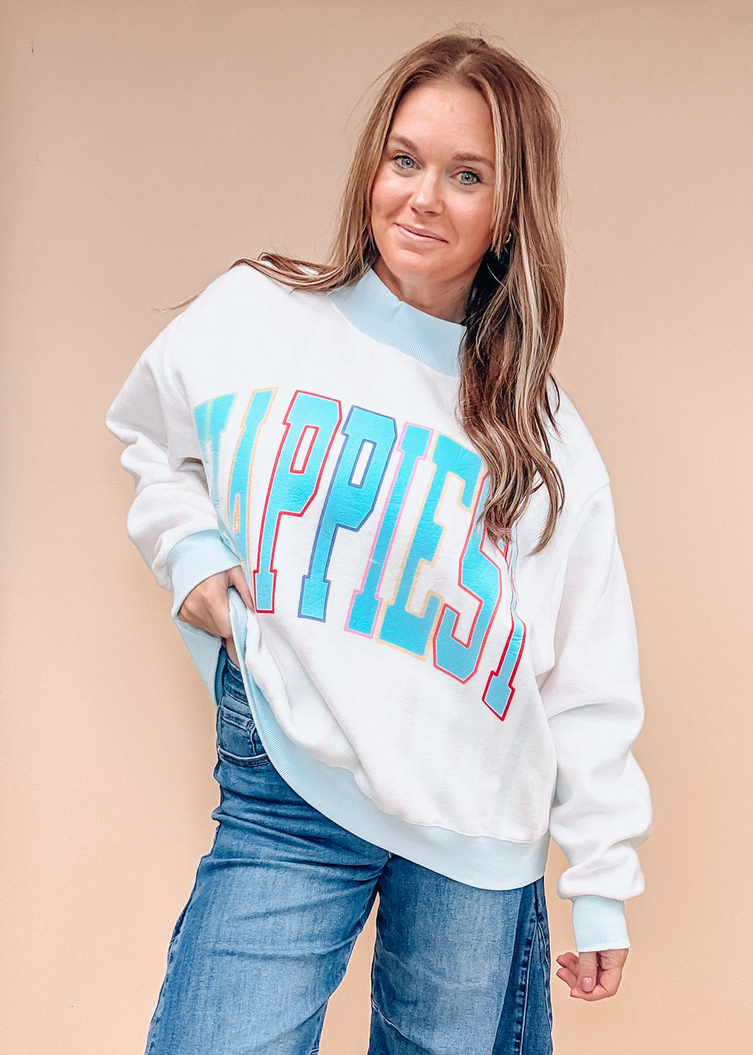 A woman modeling a white crewneck sweatshirt with &
