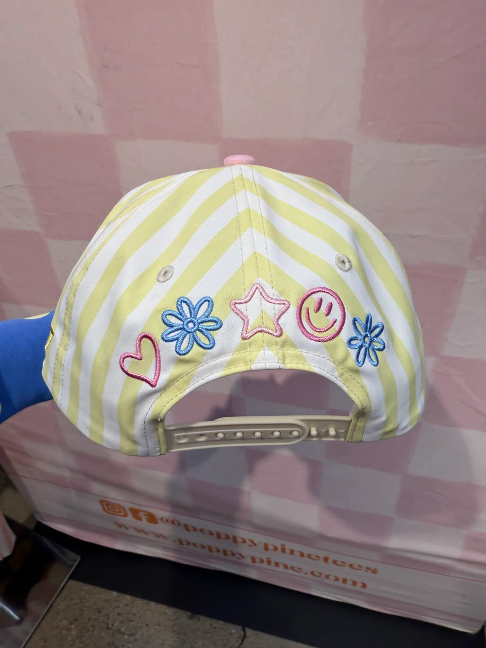 Yellow and white striped cap with colorful designs on a pink surface