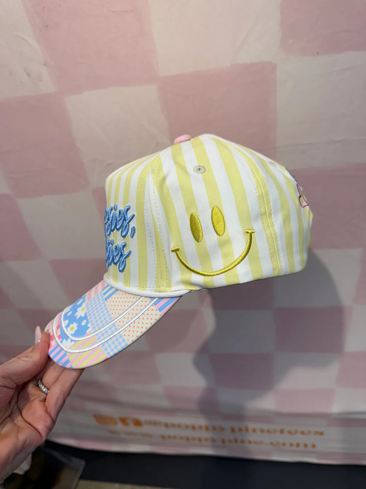 Striped baseball cap with smiley face design held against a checkered background