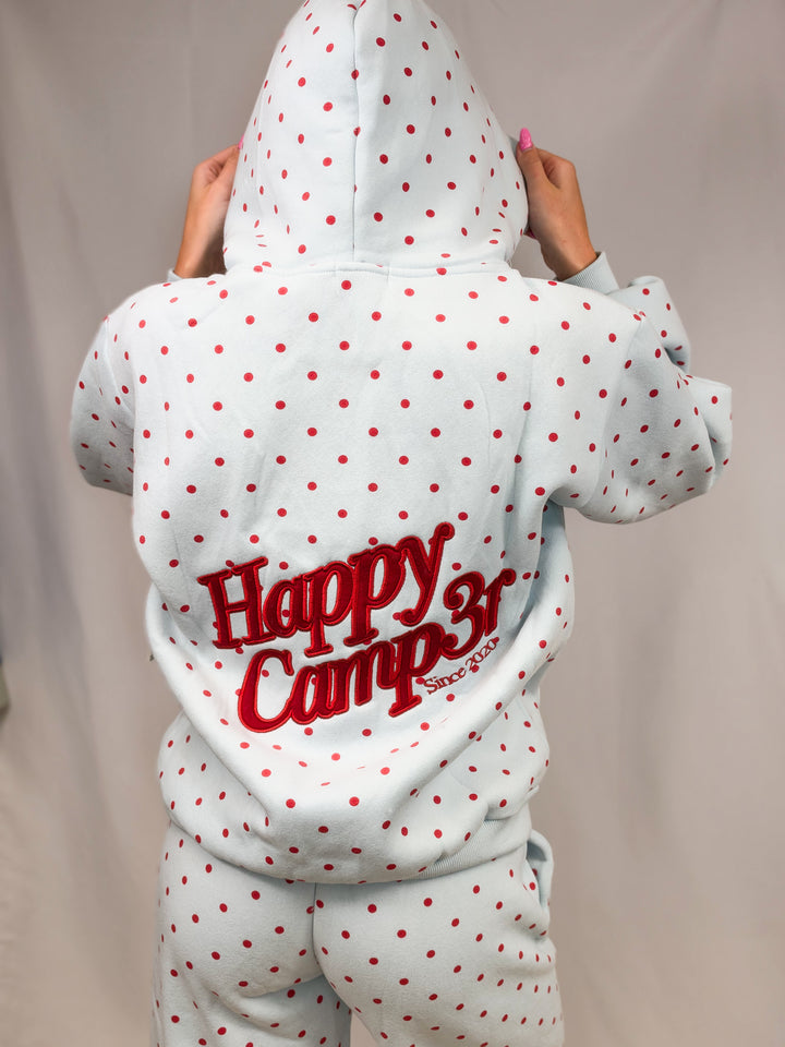 Woman shown from back wearing blue sweatshirt with red polka dots and &
