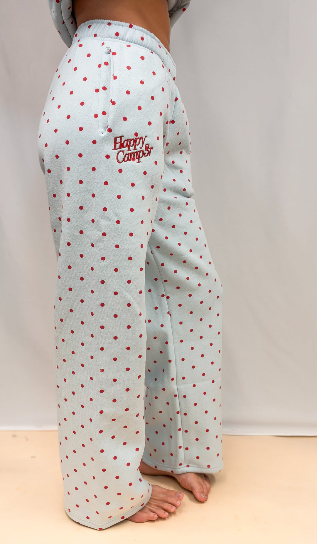 Woman shown from side view wearing blue sweatpants with red polka dots and &