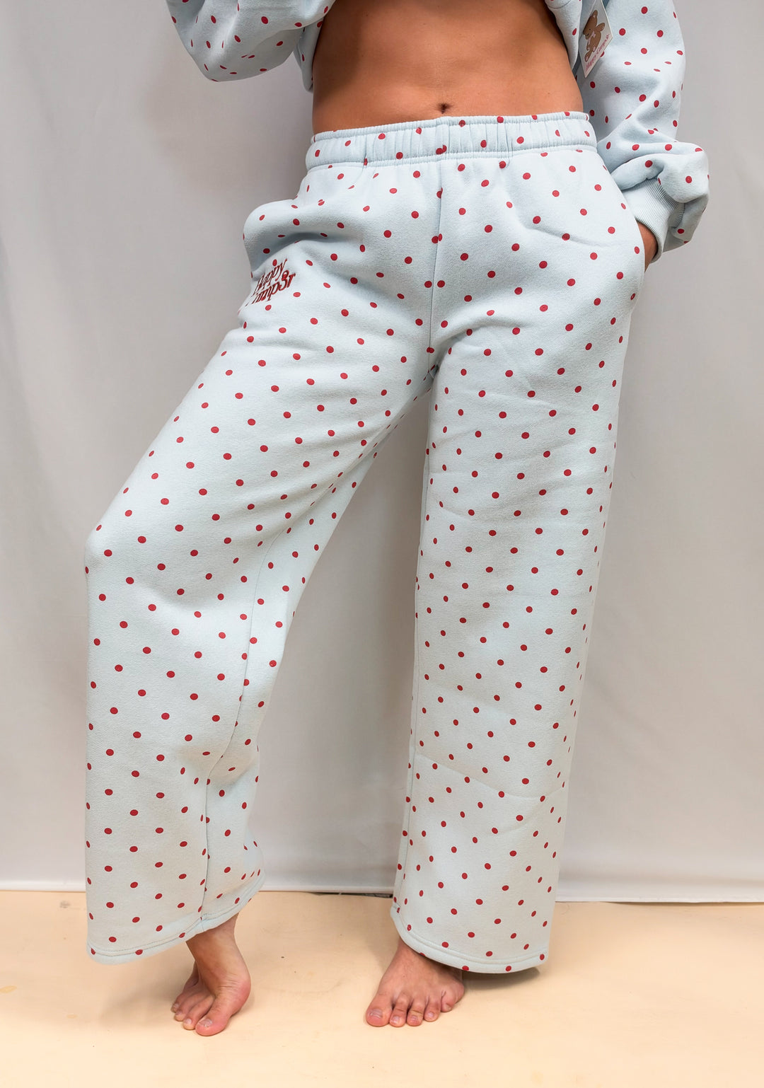 Woman wearing blue sweatpants with red polka dots on plain background