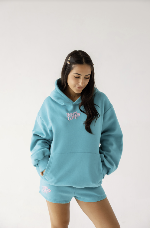 Woman wearing a light blue hoodie and shorts set with text on a white background