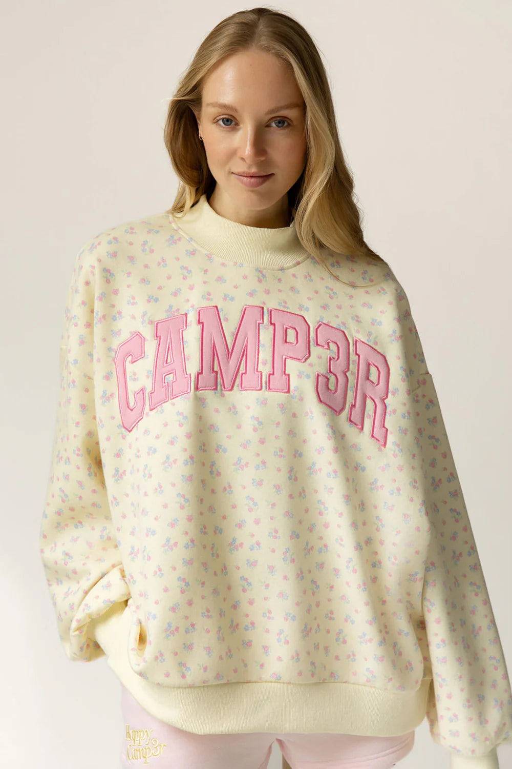 Woman wearing a light yellow sweatshirt with pink text on a plain background