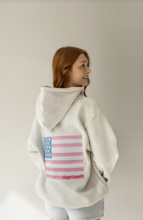 Person wearing a hoodie with an American flag design on a plain background