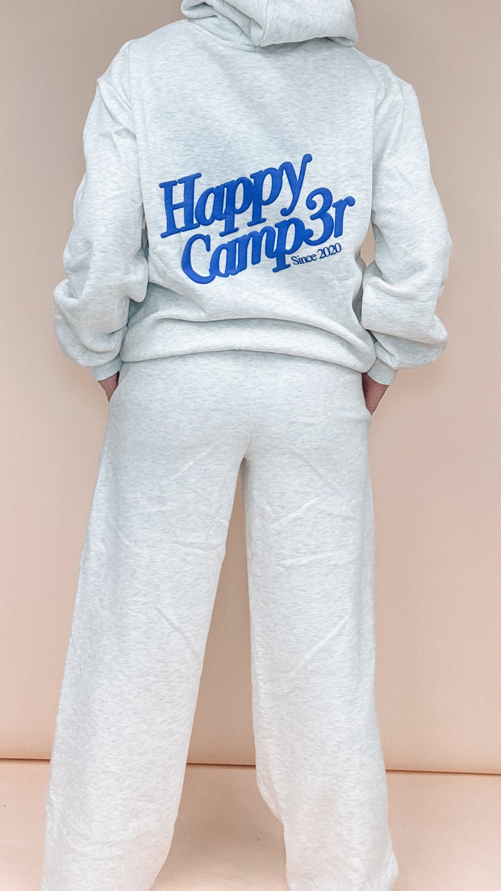 A person shown from the back wearing a light heather gray hoodie and matching sweatpants. The hoodie has &