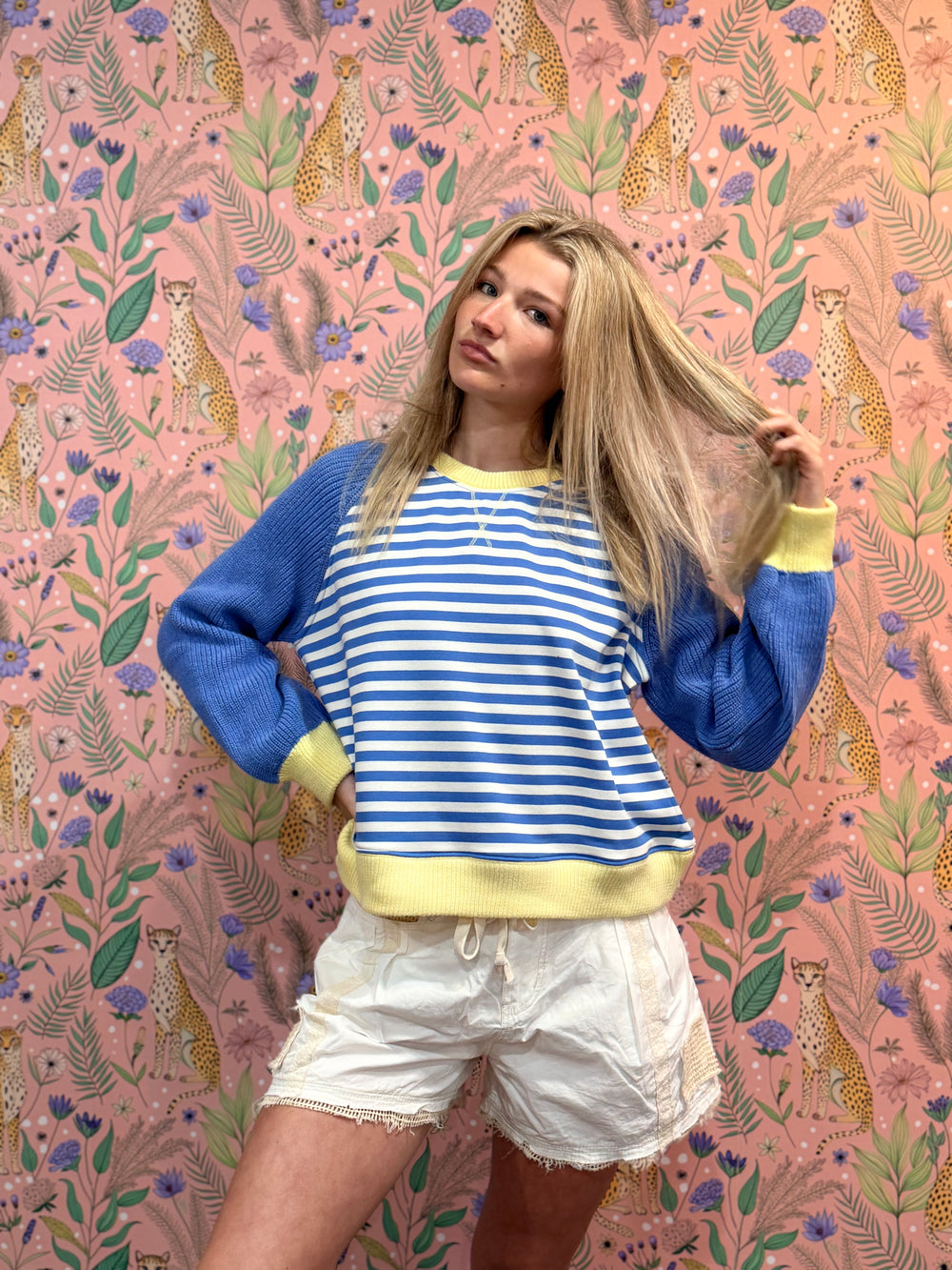 Person wearing a blue and yellow striped sweater with a colorful animal and floral patterned background