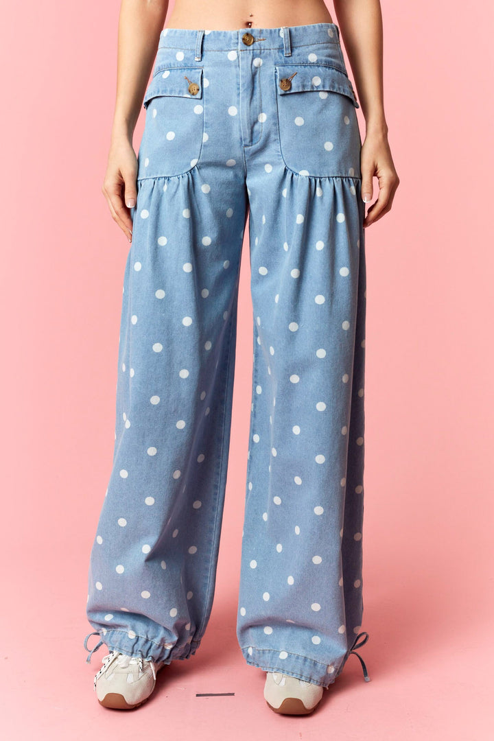 Blue polka dot pants worn by a person on a pink background