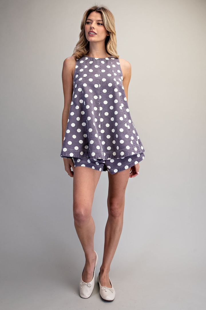 Woman wearing matching purple and white polka dot set on plain background