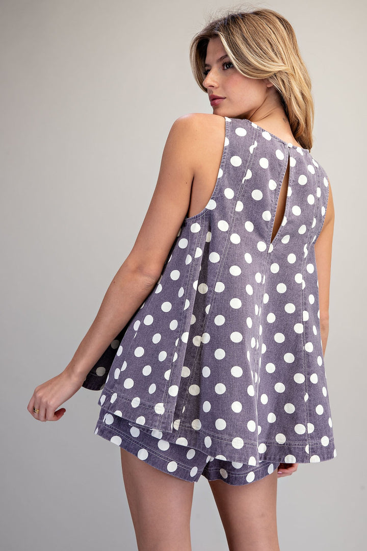 Woman wearing a polka dot dress with cut-out back on a plain background