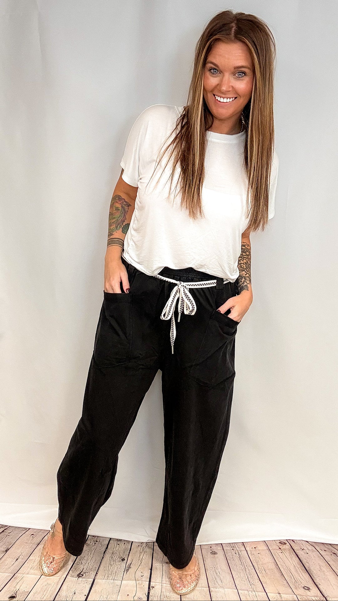 Woman wearing white short sleeve shirt and black barrel sweatpants on white background