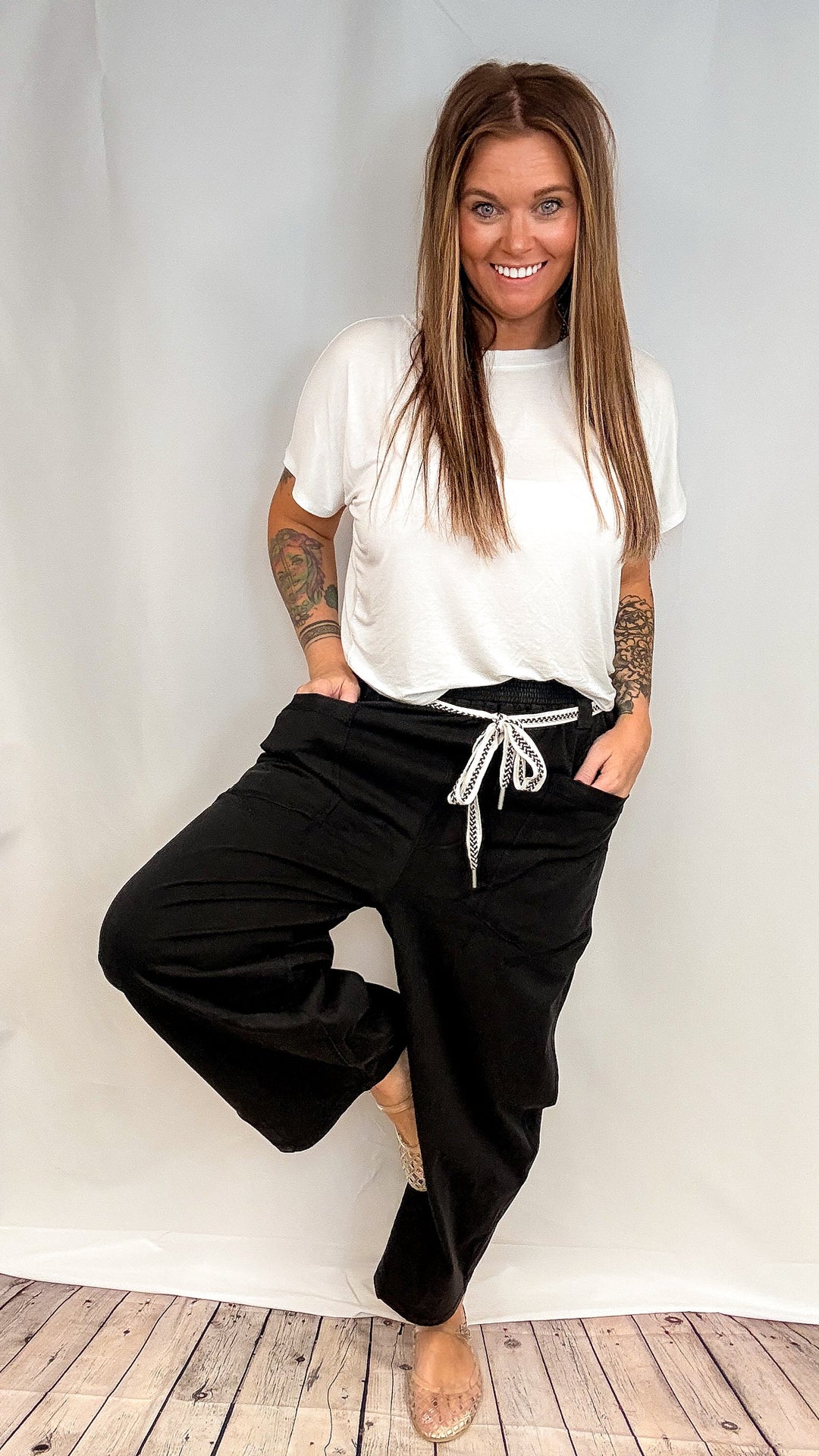 Woman wearing short sleeve white shirt and black barrel sweatpants on white background