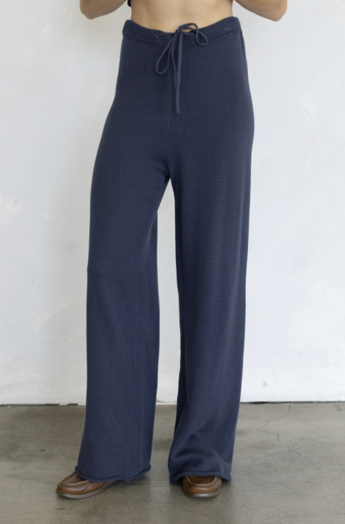 Woman wearing navy knit pants on plain background