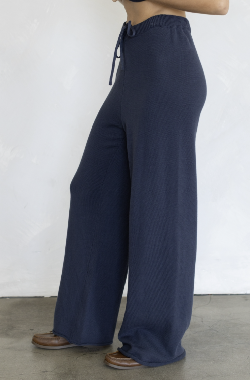 Woman wearing navy knit pants on plain background