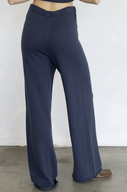 Woman shown from behind wearing navy knit pants on plain background